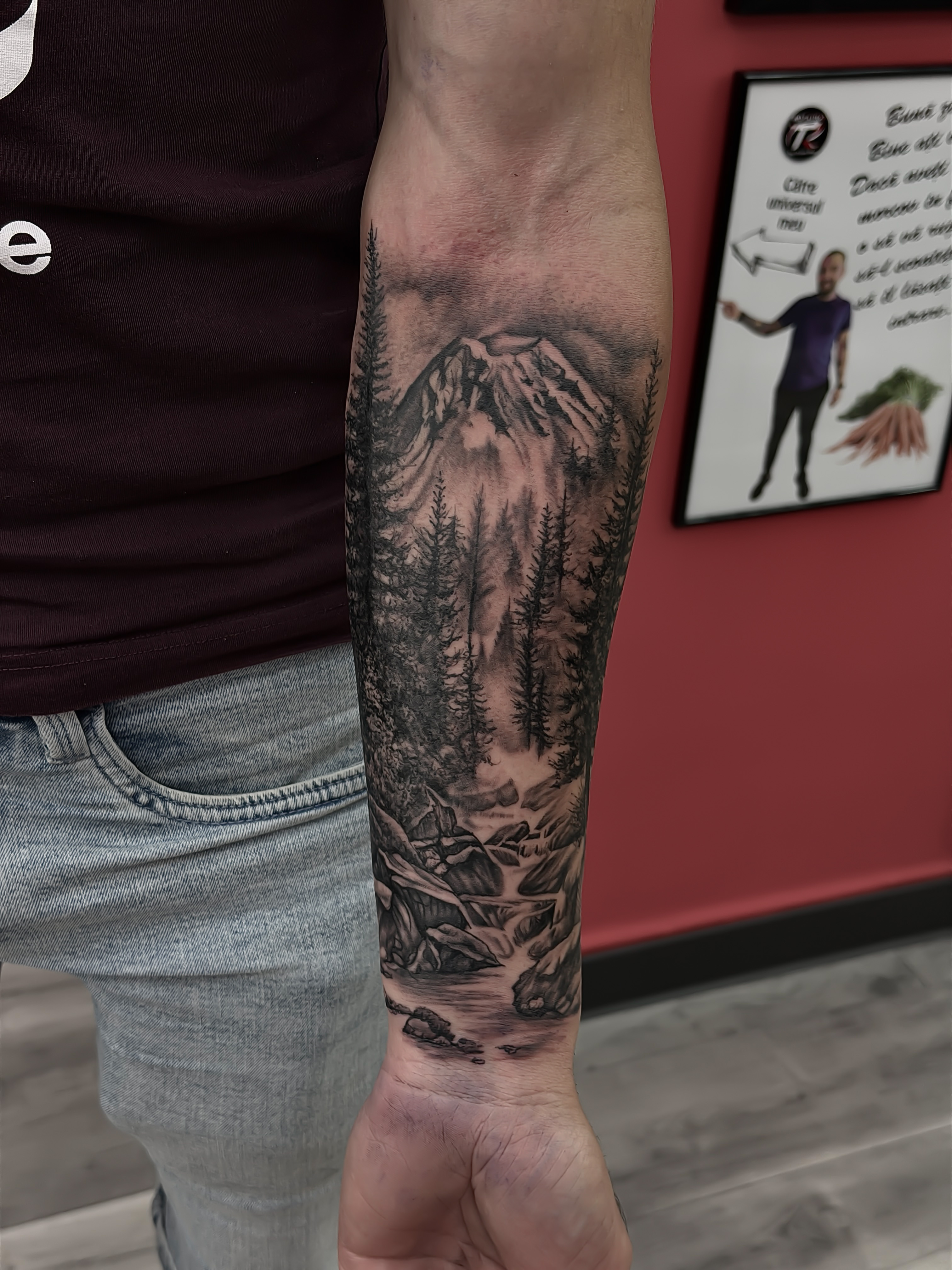 Tatuaj personalizat pe antebraț cu munte, pădure și râu